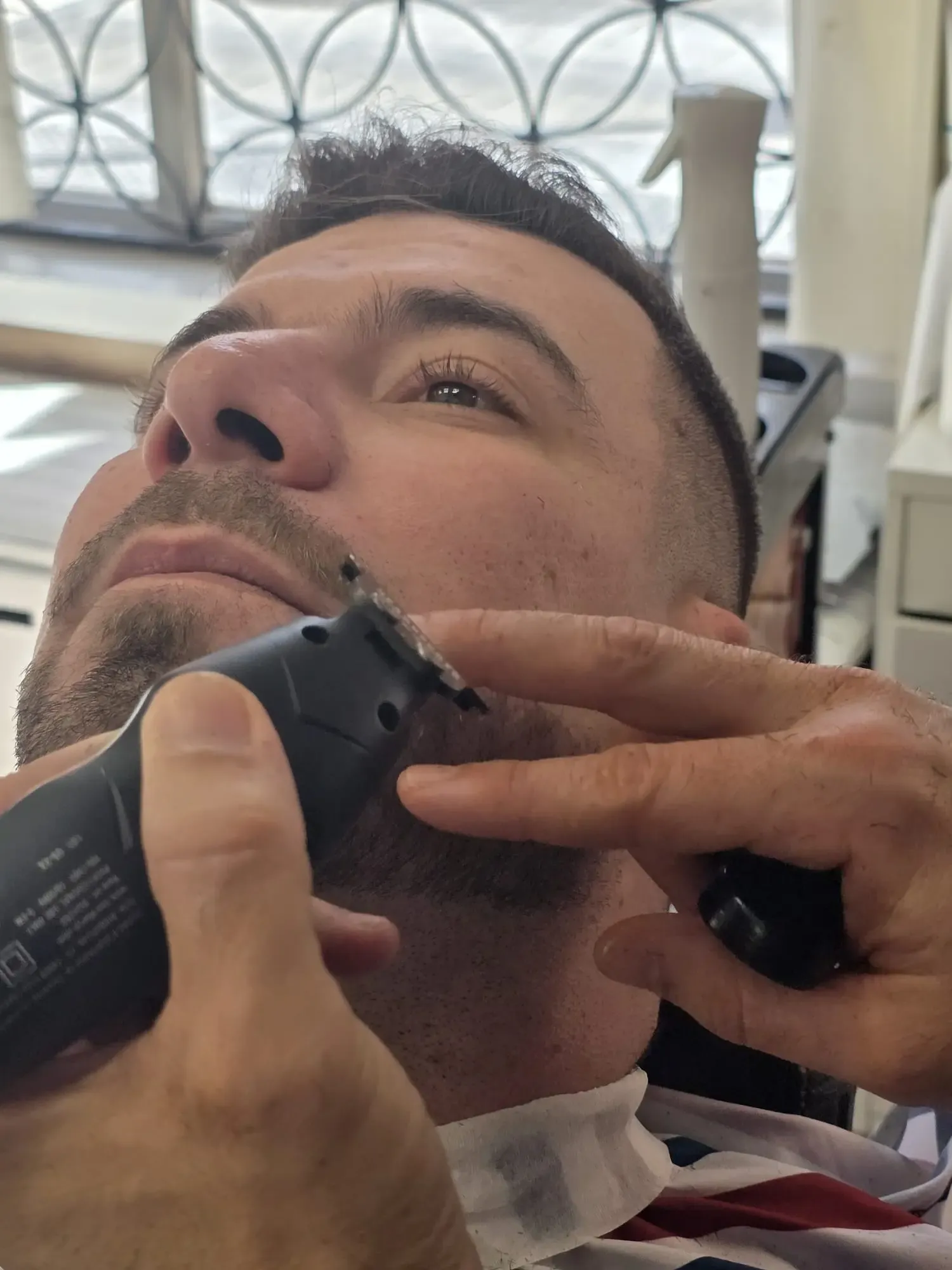 Peluquero arreglando la barba a un cliente, servicio unisex